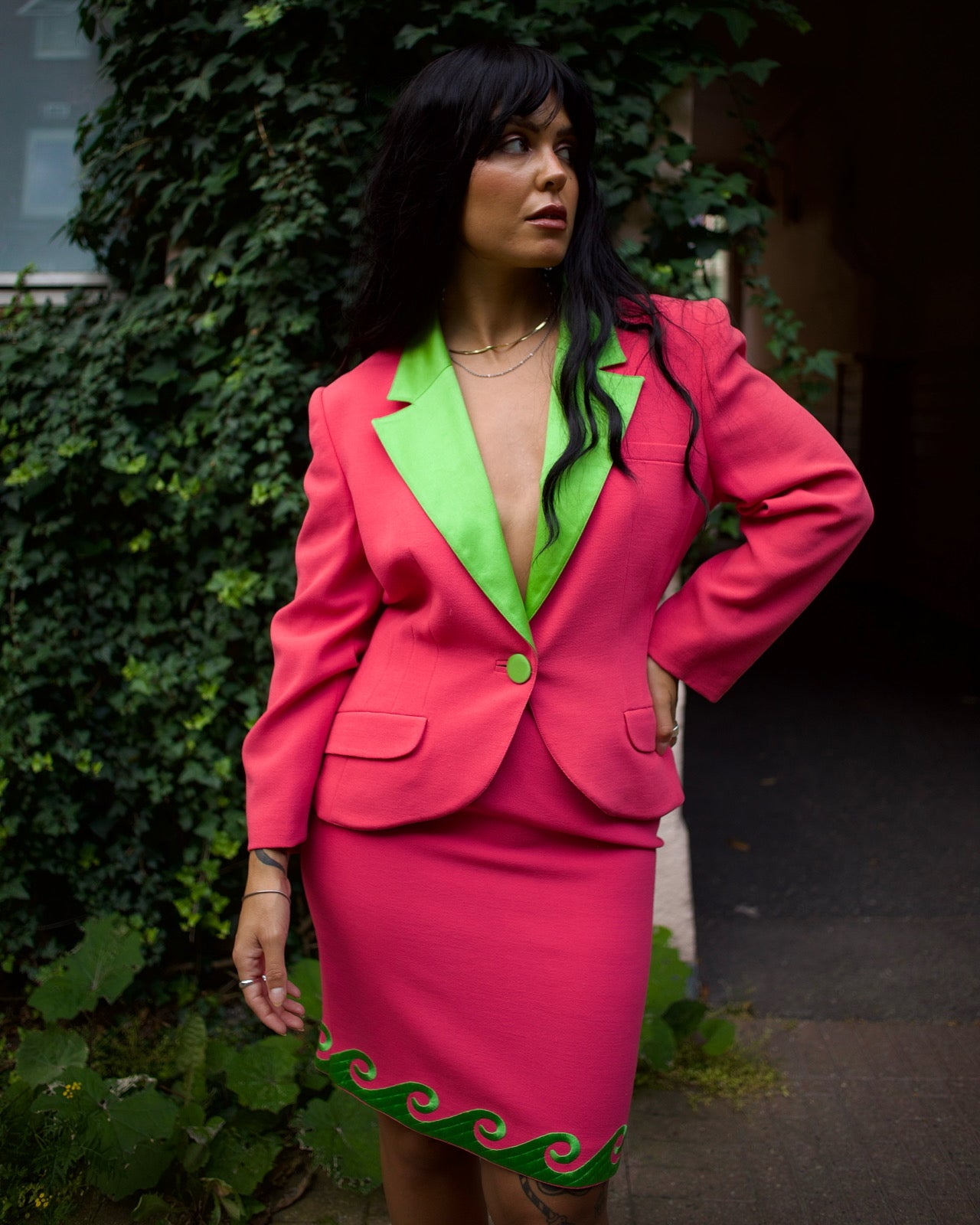 Model styling the Roccobarocco pink and green skirt suit with accessories outdoors