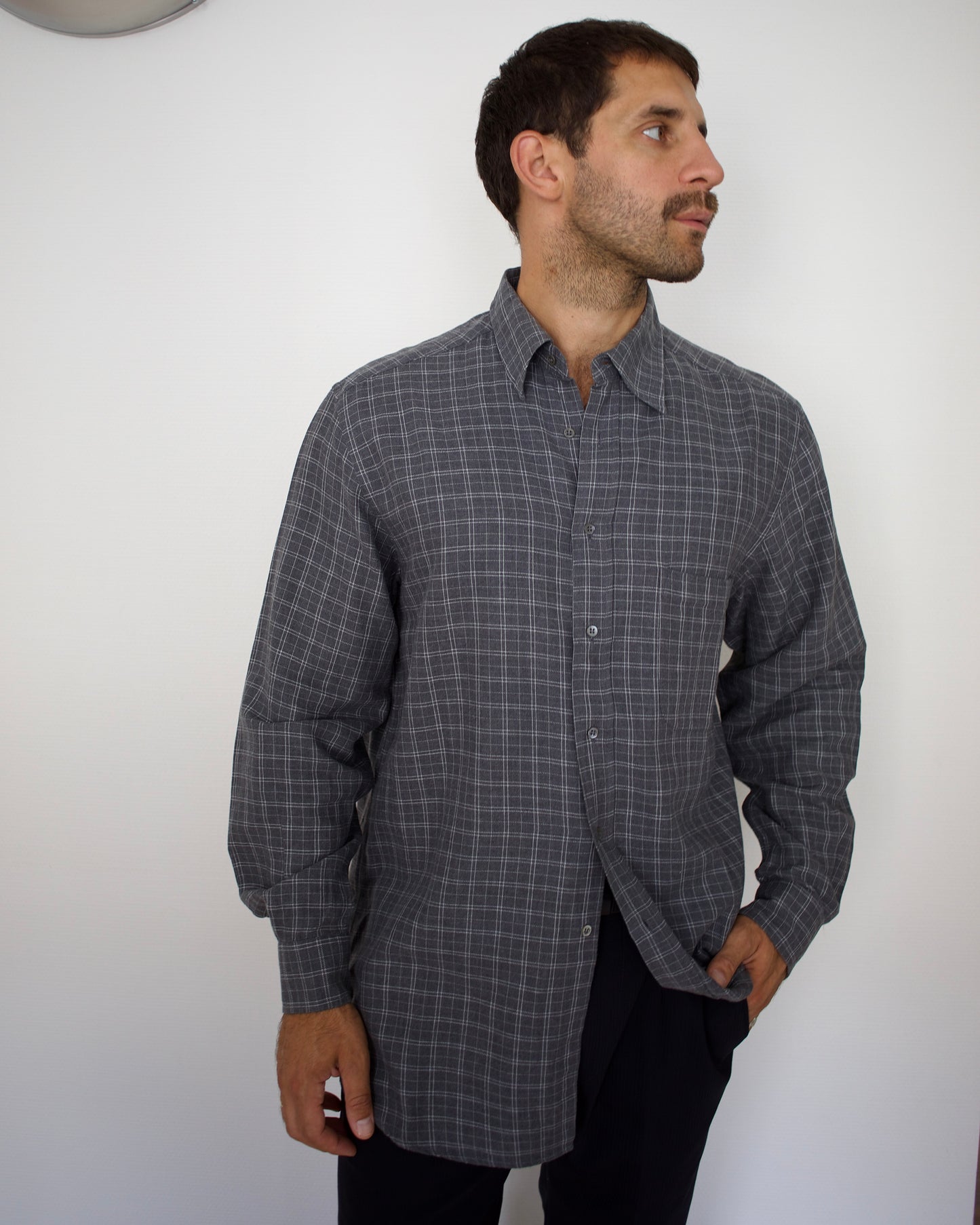 Man wearing a gray valentino checkered shirt against a white background