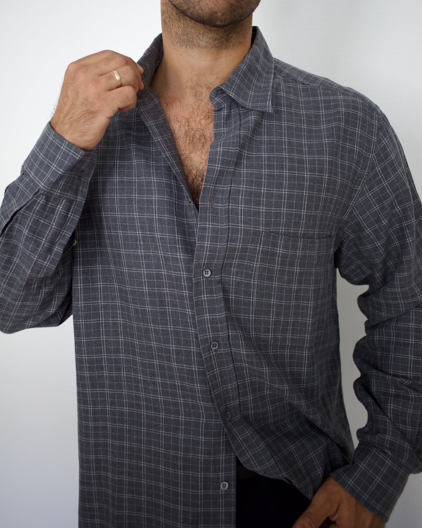 Man wearing a gray valentino checkered shirt against a white background