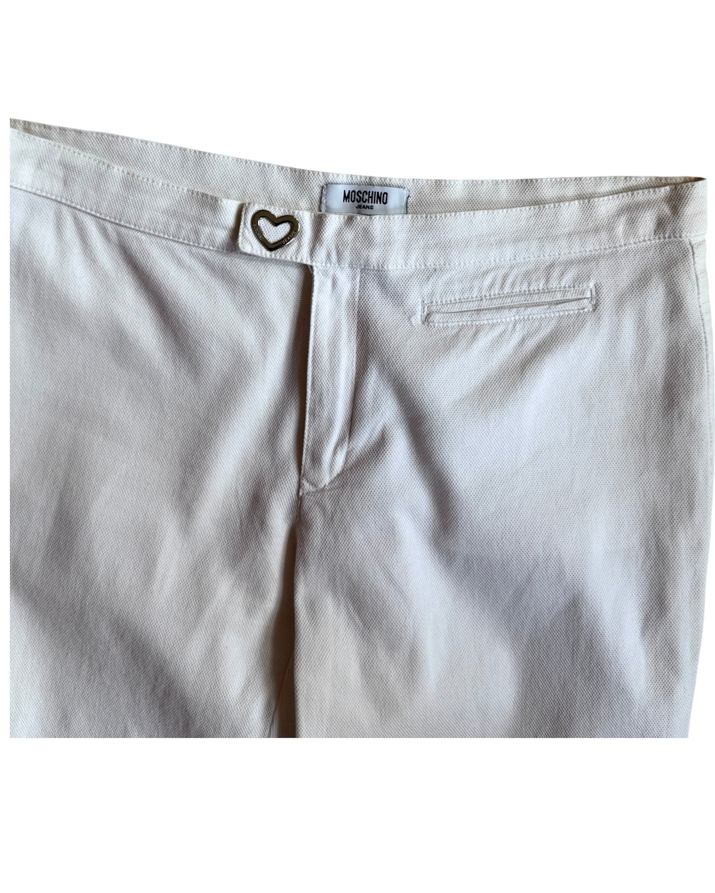 Flat lay of vintage white Moschino pants with heart-shaped button closure, straight leg fit, and mid-rise waist, displayed on a white background.