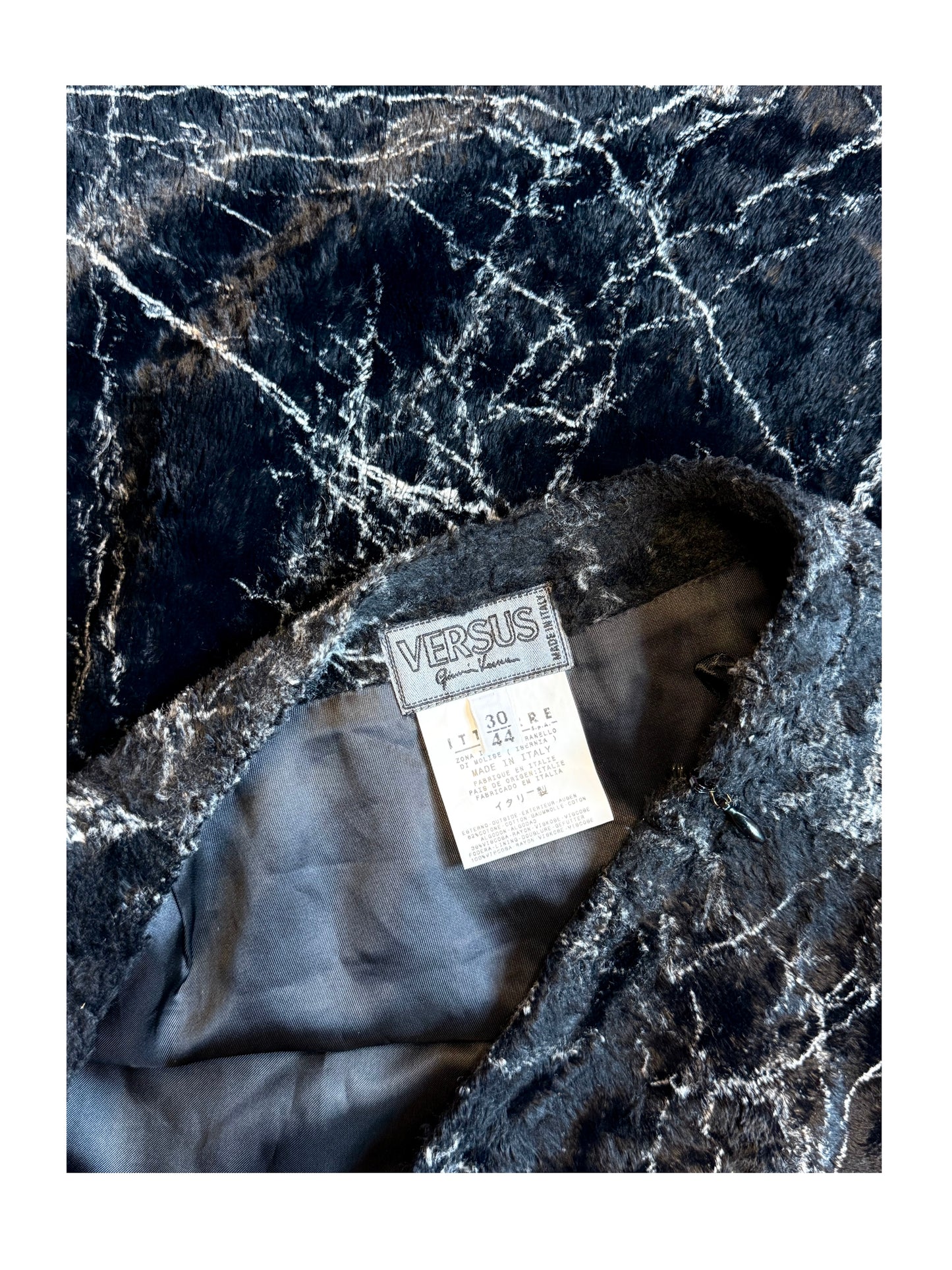 Gray fabric with a 'Versus' tag on a black marble background