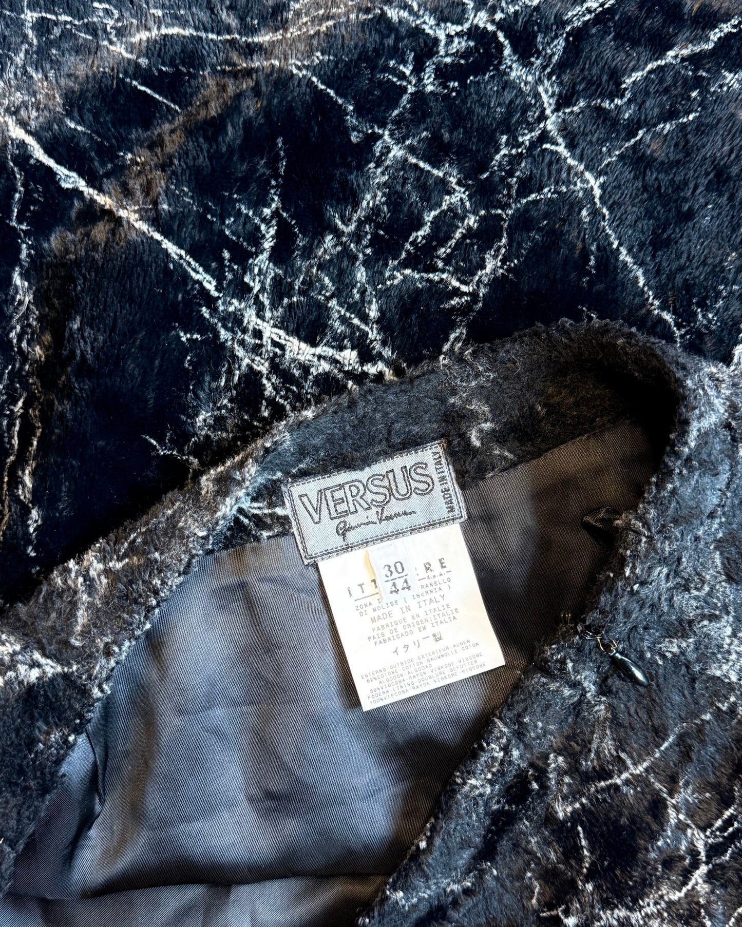 Gray fabric with a 'Versus' tag on a black marble background