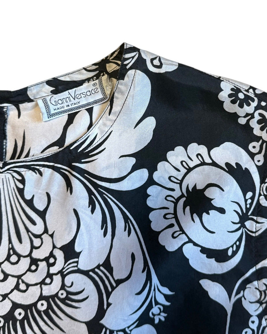 Black Gianni Versace top with white floral patterns on a white background