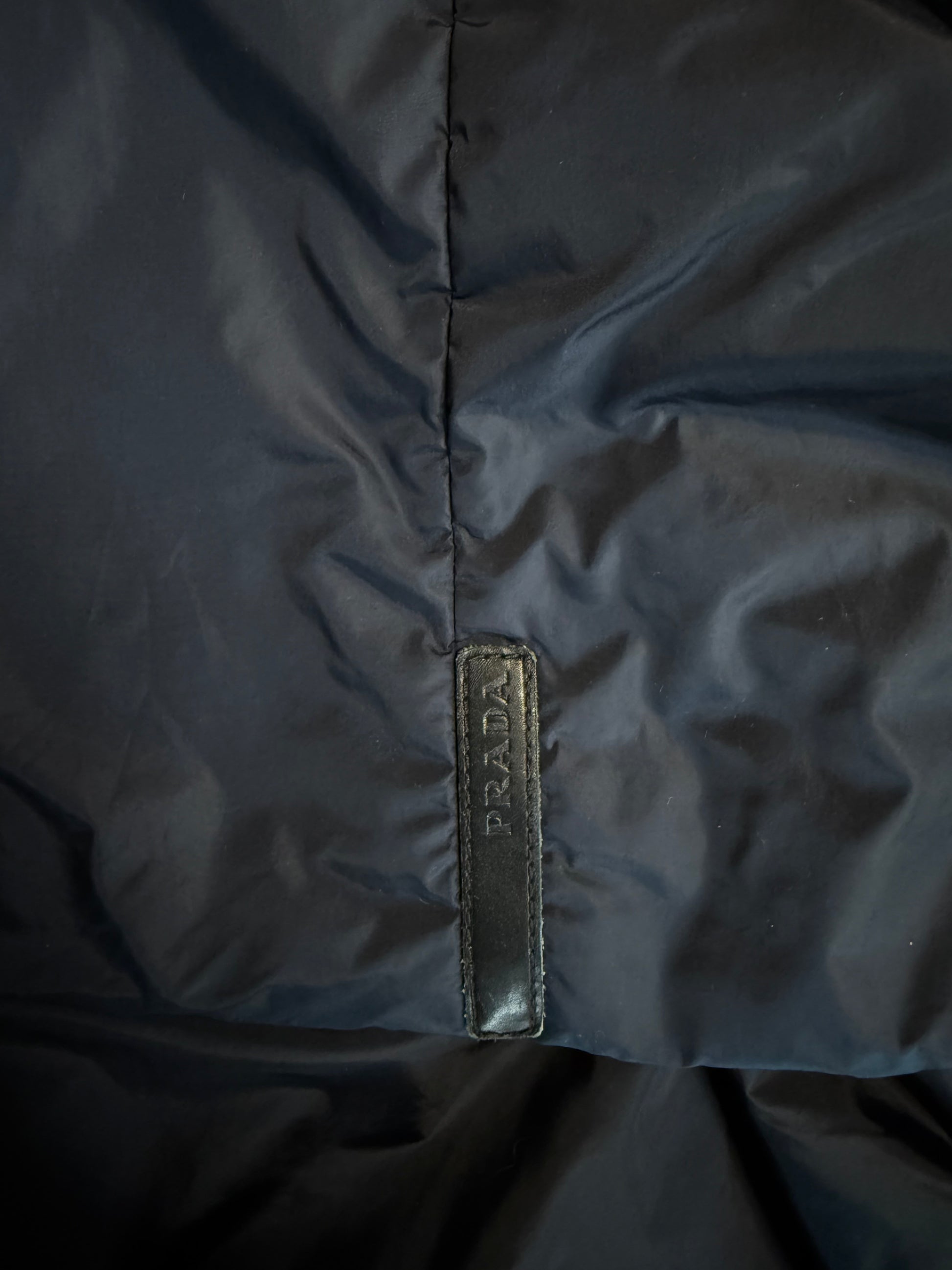 Close-up of a dark blue fabric with a brand label on a matching background