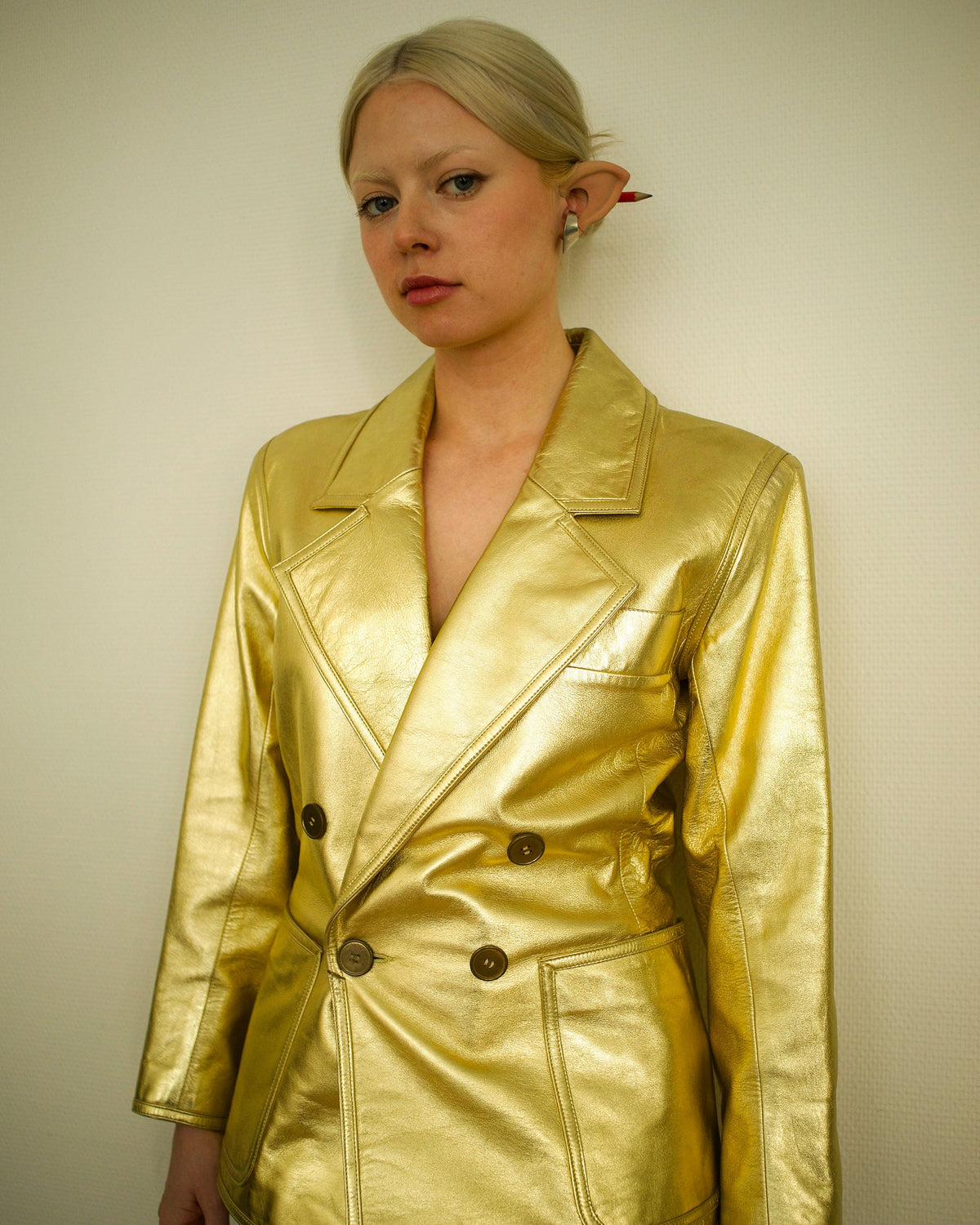 Person wearing a shiny gold jacket against a plain background