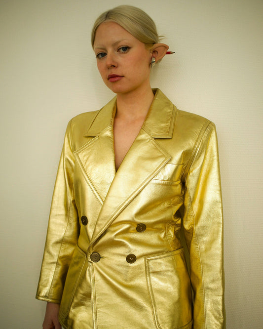 Person wearing a shiny gold jacket against a plain background