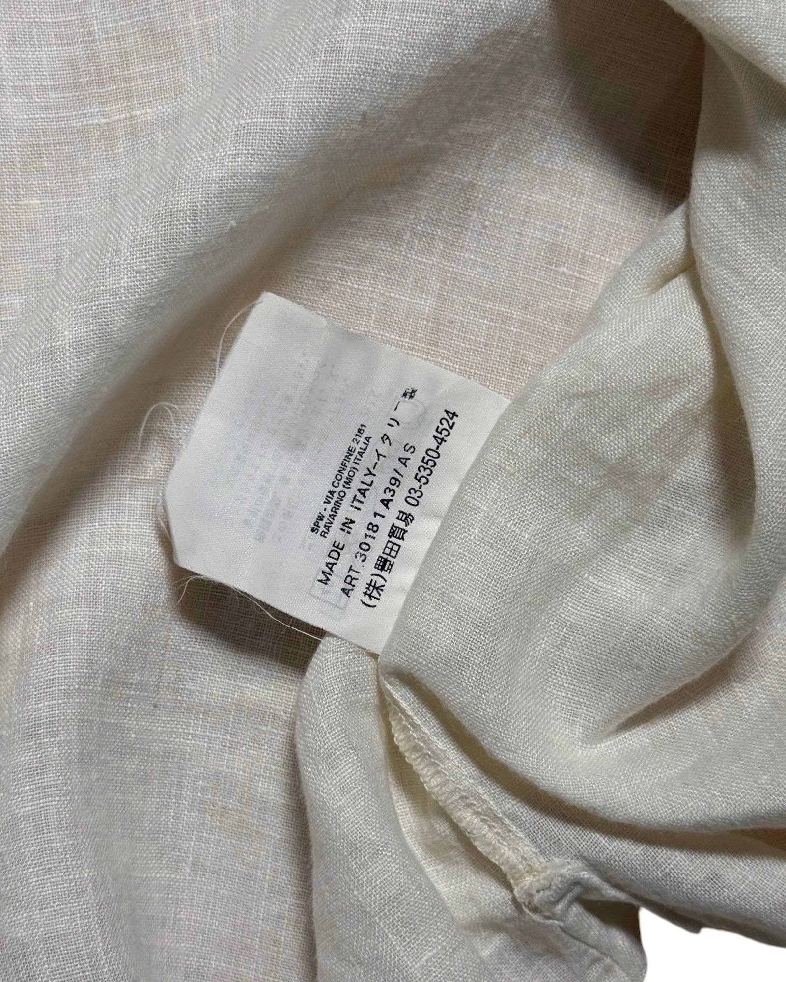 Close-up of a light beige or off-white woven fabric with a sewn-in white product CP Company tag