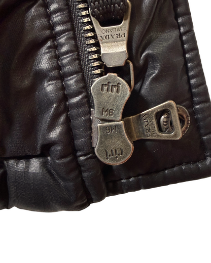 Close-up of a puffer jacket with bronze zipper pulls engraved with 'Prada Milano' and riri.