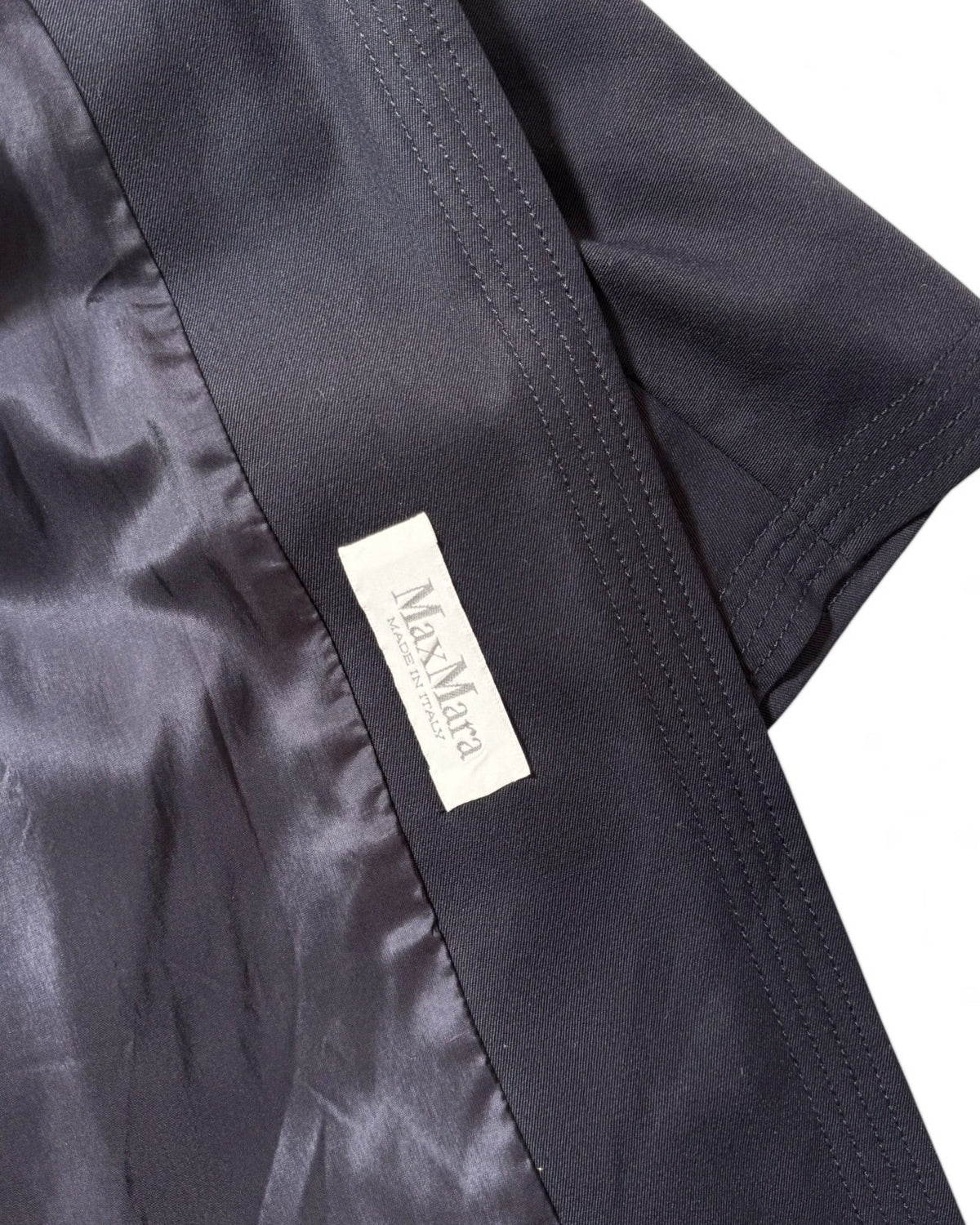 Close-up of a dark navy satin-like garment with a visible white fabric label reading Max Mara.