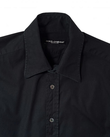 Close-up of a black long-sleeve button-down shirt by Dolce & Gabbana, showing the collar, front buttons, and inner neck label on a white background.
