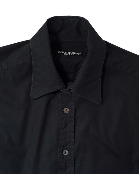 Close-up of a black long-sleeve button-down shirt by Dolce & Gabbana, showing the collar, front buttons, and inner neck label on a white background.
