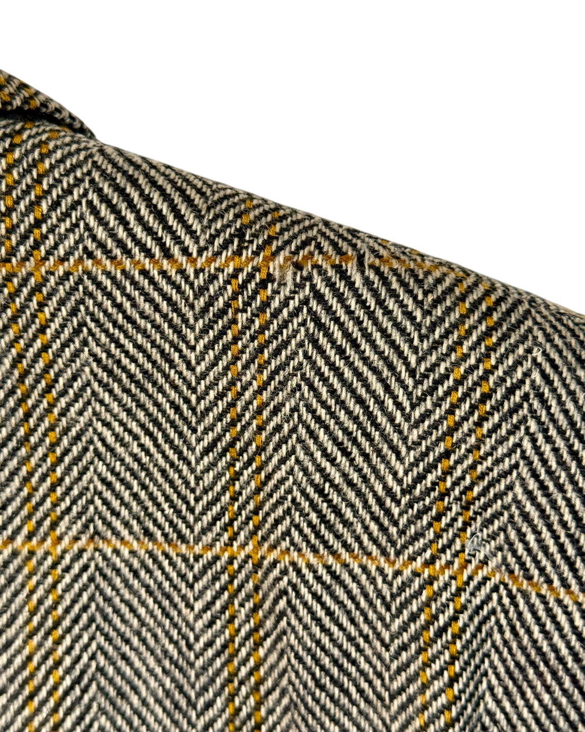 Close-up of a vintage valentino herringbone patterned fabric in black, beige, and yellow with a white background.
