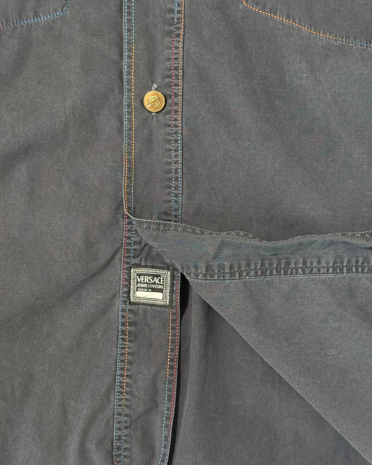 Close-up of a dark gray jshirtwith a Versace label on a plain background