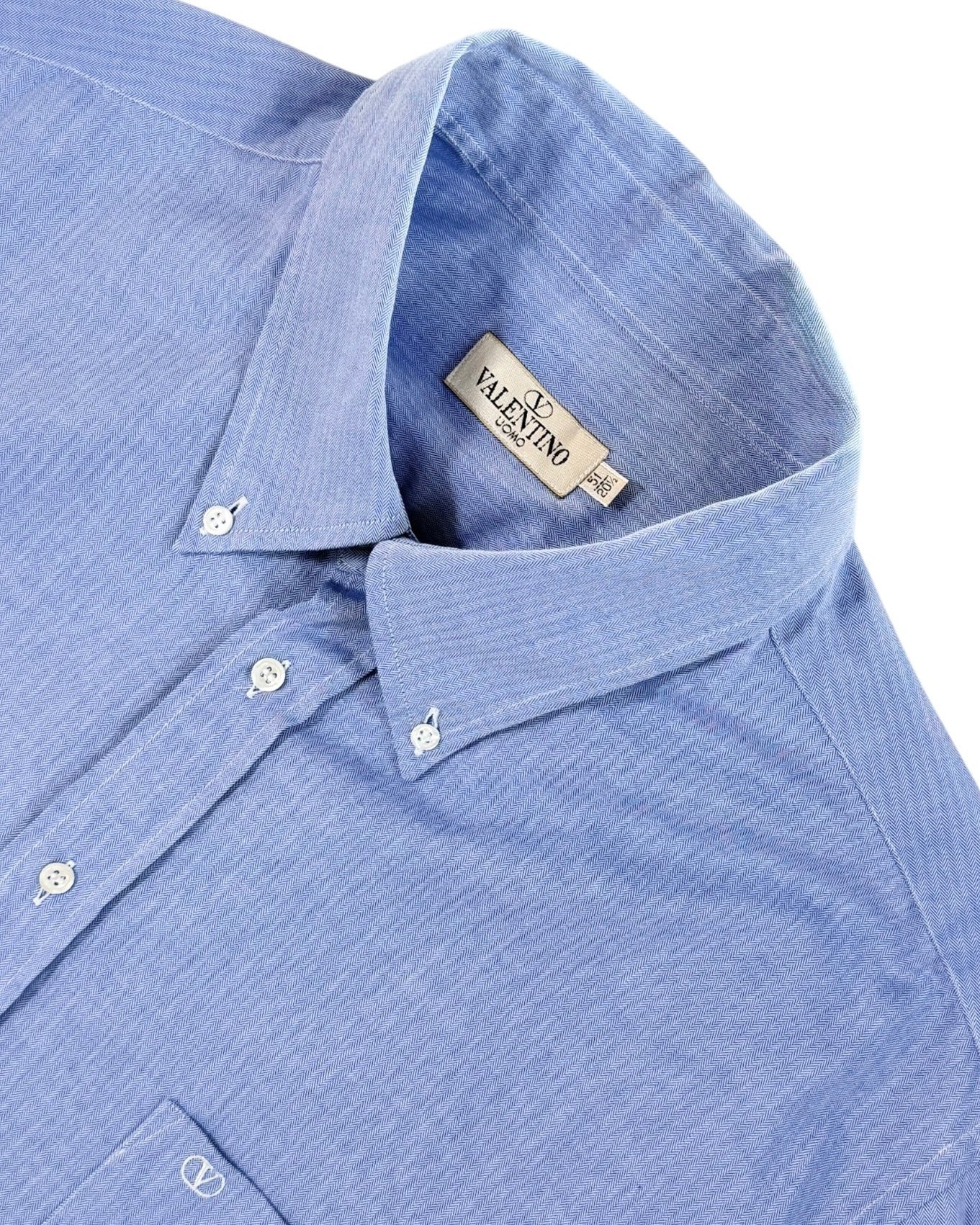 Close-up of a blue shirt with a Valentino label on a white background